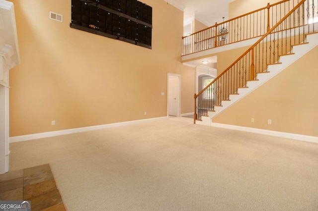 unfurnished living room featuring a towering ceiling and carpet floors