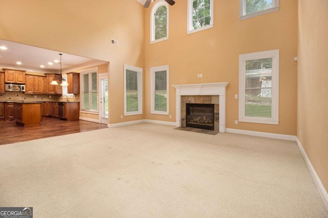 unfurnished living room featuring a fireplace, sink, a notable chandelier, and light hardwood / wood-style floors