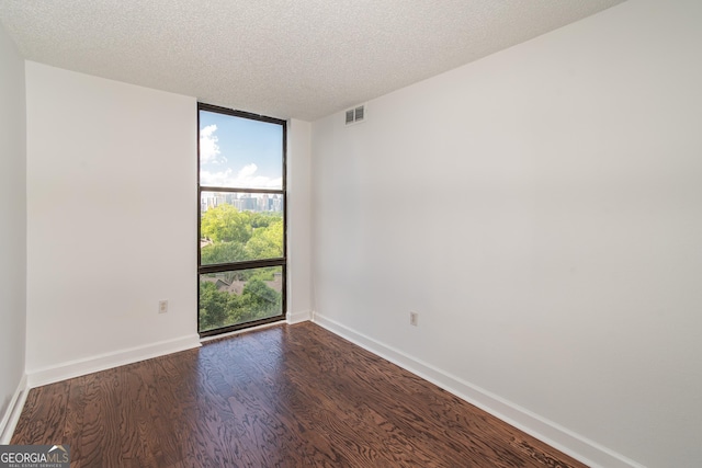 empty room with a textured ceiling and dark wood-type flooring