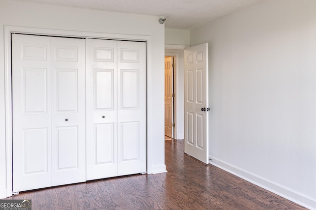 unfurnished bedroom with a closet, dark hardwood / wood-style flooring, and a textured ceiling