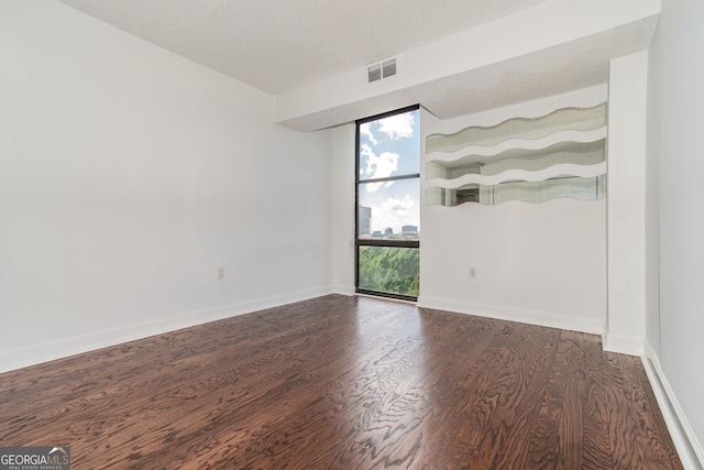 spare room with a textured ceiling, dark hardwood / wood-style flooring, and expansive windows