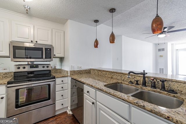 kitchen with light stone countertops, sink, stainless steel appliances, and white cabinetry