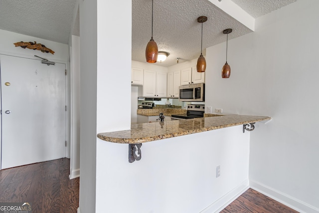 kitchen with white cabinetry, hanging light fixtures, appliances with stainless steel finishes, and a textured ceiling