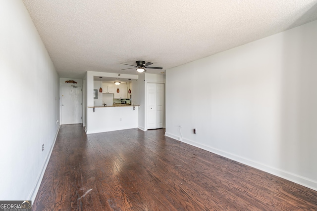 unfurnished living room featuring ceiling fan, dark hardwood / wood-style floors, and a textured ceiling