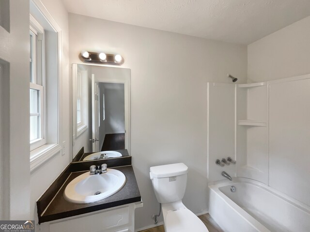 full bathroom featuring a textured ceiling, vanity, toilet, and washtub / shower combination