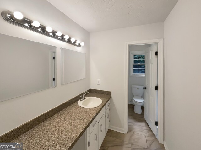 bathroom featuring a textured ceiling, vanity, and toilet