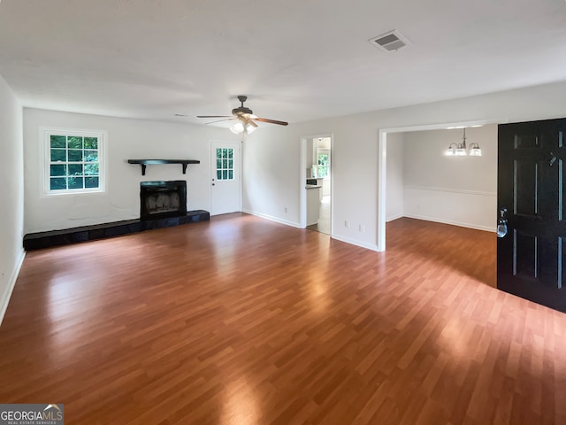 unfurnished living room featuring dark wood-type flooring and ceiling fan with notable chandelier