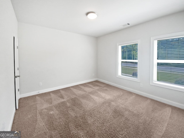 unfurnished room with carpet, visible vents, and baseboards