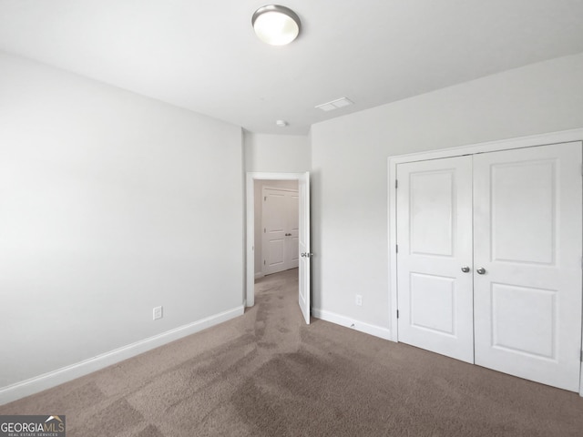 unfurnished bedroom with a closet, visible vents, baseboards, and carpet