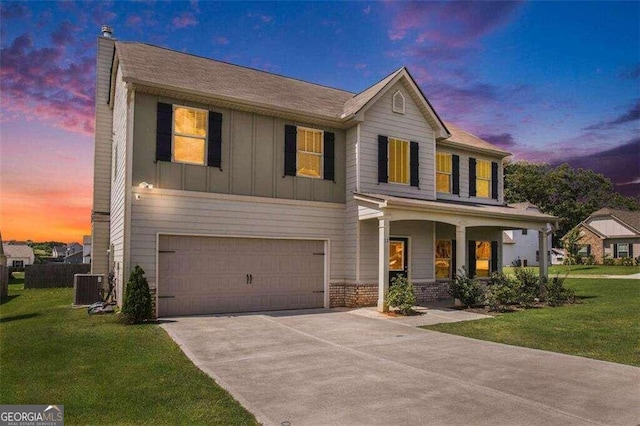 view of front of home with a yard, cooling unit, and a garage