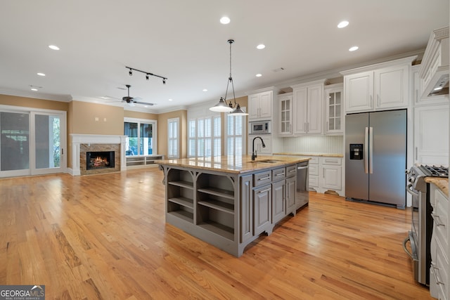 kitchen featuring rail lighting, stainless steel appliances, white cabinets, and a premium fireplace