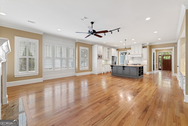 unfurnished living room featuring crown molding, ceiling fan, rail lighting, and light hardwood / wood-style floors