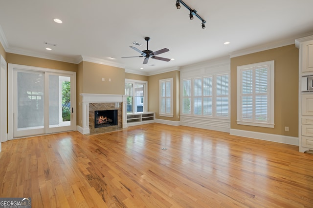 unfurnished living room featuring a fireplace, light hardwood / wood-style flooring, track lighting, ceiling fan, and ornamental molding