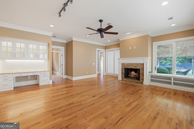 unfurnished living room featuring light wood-type flooring, rail lighting, ceiling fan, and a fireplace