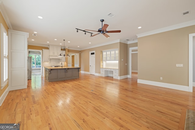 unfurnished living room featuring ceiling fan, ornamental molding, and light hardwood / wood-style flooring