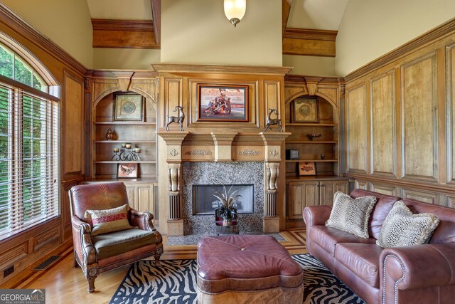 living room featuring a premium fireplace, ornamental molding, high vaulted ceiling, and light hardwood / wood-style floors