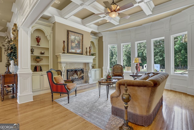 living room with coffered ceiling, a fireplace, beam ceiling, light hardwood / wood-style floors, and ceiling fan