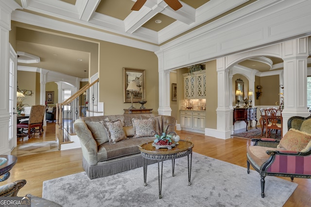 living room featuring decorative columns, plenty of natural light, and light hardwood / wood-style flooring