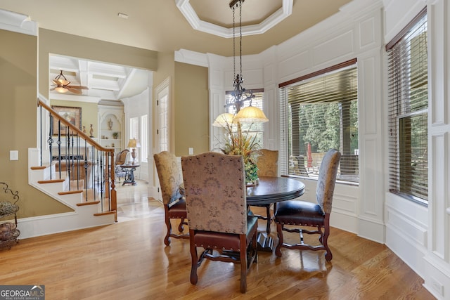 dining room featuring coffered ceiling, ceiling fan with notable chandelier, crown molding, and light hardwood / wood-style flooring