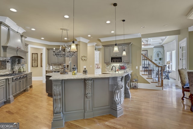 kitchen featuring crown molding, hanging light fixtures, a spacious island, and light hardwood / wood-style floors