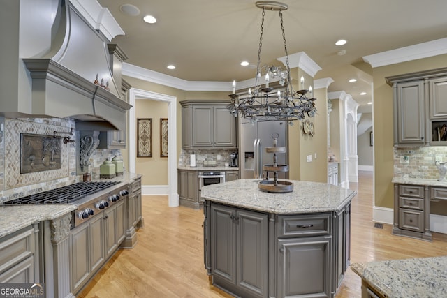 kitchen featuring gray cabinetry, a center island, crown molding, light hardwood / wood-style flooring, and stainless steel appliances