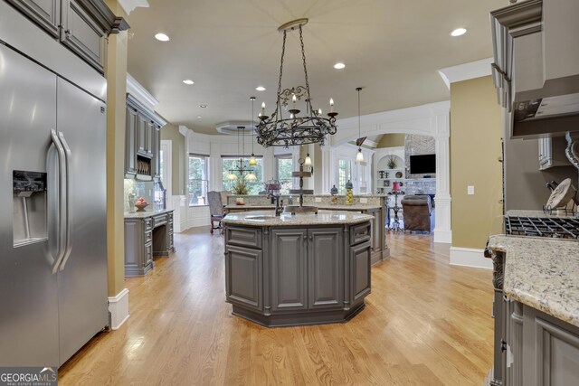 kitchen with gray cabinetry, decorative light fixtures, light wood-type flooring, and built in refrigerator