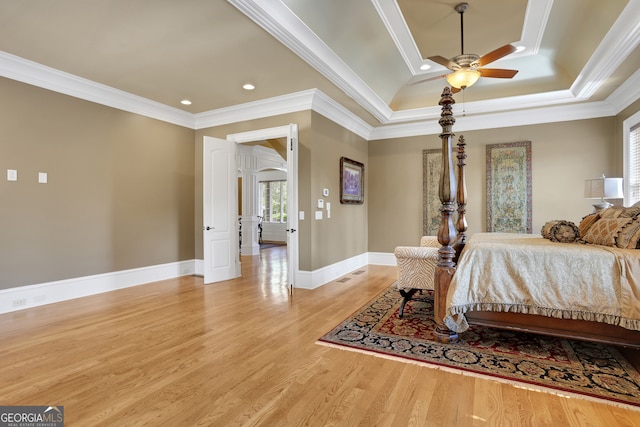 bedroom featuring light wood-type flooring, ceiling fan, a raised ceiling, and crown molding