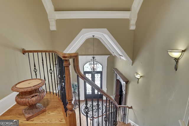 stairway with crown molding, a chandelier, and hardwood / wood-style flooring