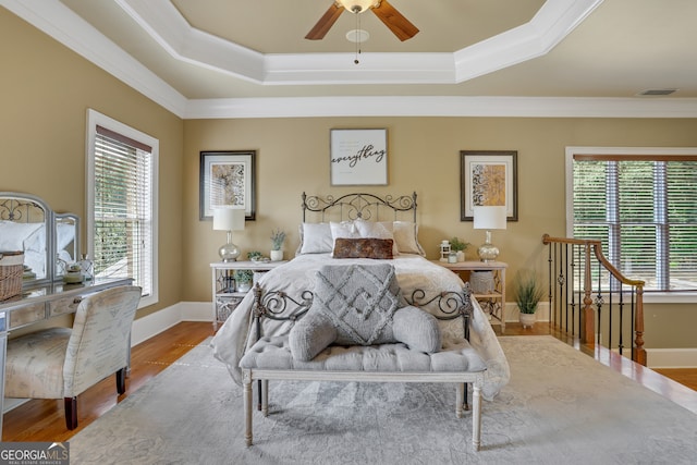 bedroom featuring multiple windows, ceiling fan, hardwood / wood-style flooring, and ornamental molding