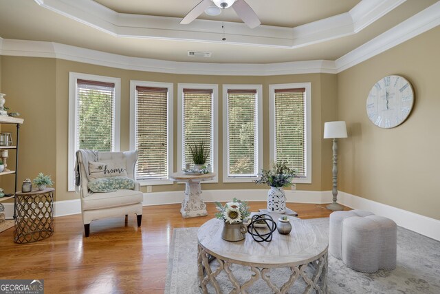 sitting room with crown molding, a raised ceiling, hardwood / wood-style floors, and ceiling fan