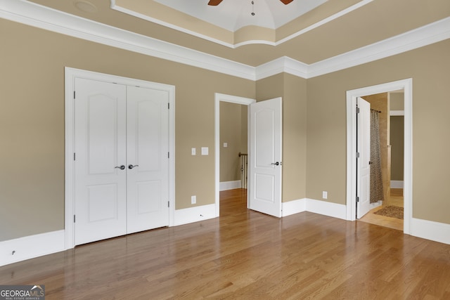 unfurnished bedroom with crown molding, connected bathroom, wood-type flooring, ceiling fan, and a closet