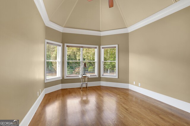 empty room with high vaulted ceiling, hardwood / wood-style floors, ceiling fan, and ornamental molding