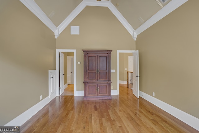 unfurnished bedroom featuring crown molding, high vaulted ceiling, and light wood-type flooring