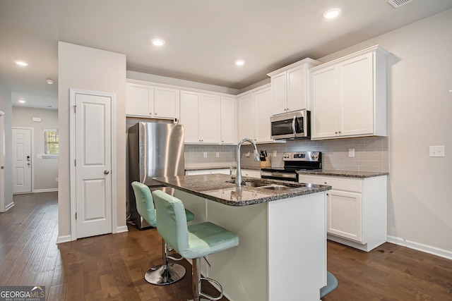 kitchen featuring dark wood-type flooring, stainless steel appliances, dark stone countertops, and white cabinets