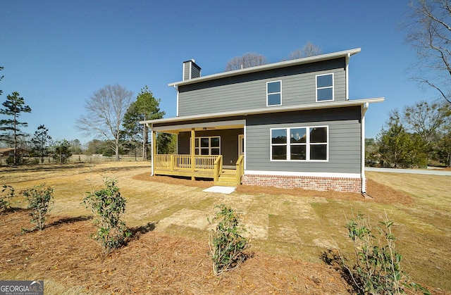 rear view of property with a chimney and a yard