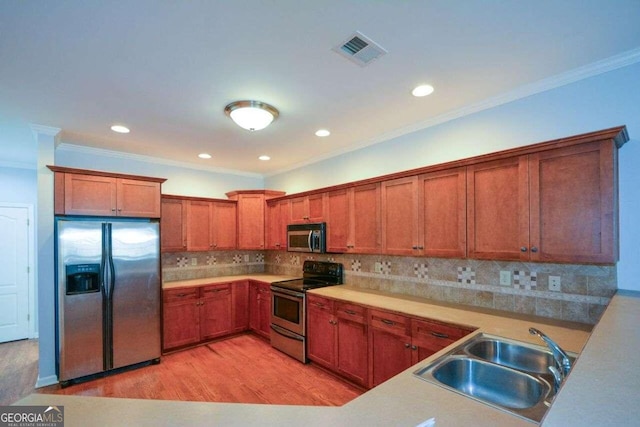 kitchen with crown molding, appliances with stainless steel finishes, light hardwood / wood-style flooring, and sink