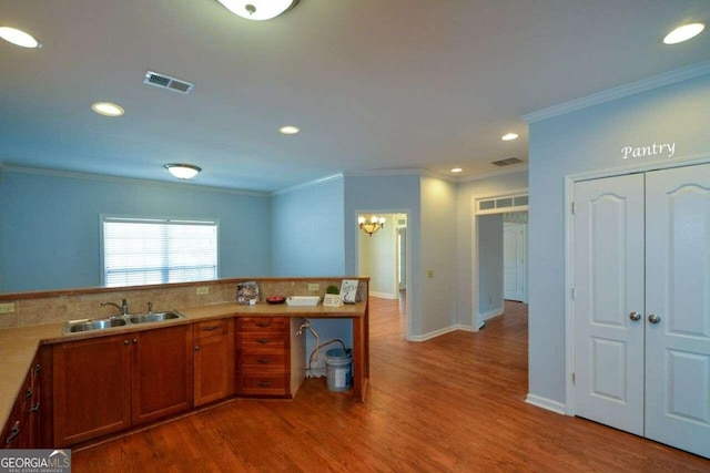 6865 Cowan Mill Rd, Winston, GA 30187 - kitchen with ornamental molding, recessed lighting, brown cabinetry, a sink, and wood finished floors