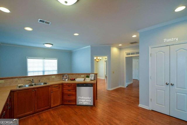 kitchen featuring dishwasher, ornamental molding, hardwood / wood-style floors, and sink