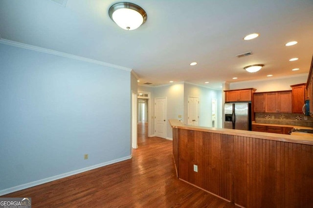 kitchen featuring crown molding, backsplash, stainless steel appliances, kitchen peninsula, and dark hardwood / wood-style floors