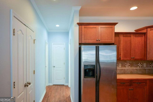 kitchen featuring ornamental molding, stainless steel fridge, light wood-type flooring, and tasteful backsplash