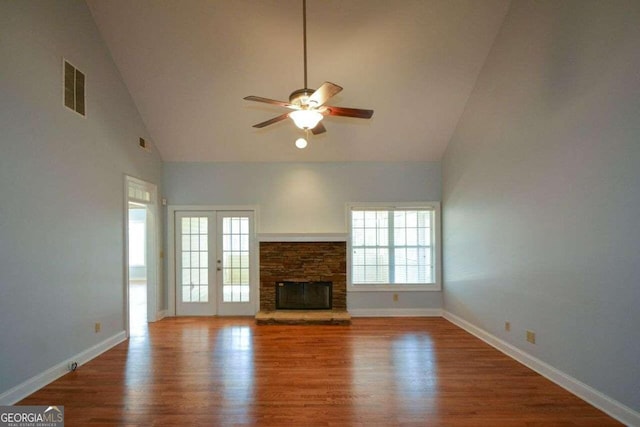 unfurnished living room featuring a fireplace, high vaulted ceiling, wood-type flooring, ceiling fan, and french doors