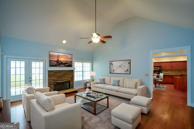 living room with a fireplace, high vaulted ceiling, hardwood / wood-style floors, ceiling fan, and french doors