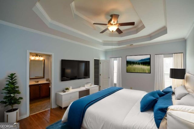 bedroom with dark hardwood / wood-style flooring, a tray ceiling, crown molding, ensuite bath, and ceiling fan