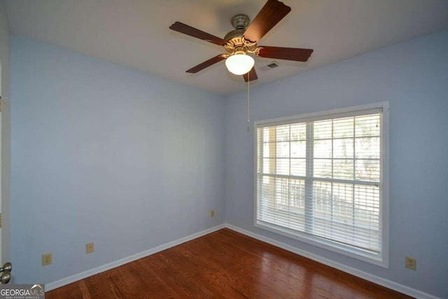 spare room featuring dark wood-type flooring and ceiling fan