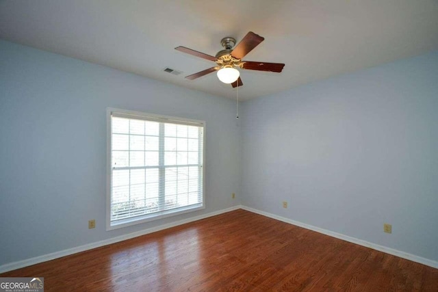 empty room with ceiling fan, a wealth of natural light, and hardwood / wood-style flooring