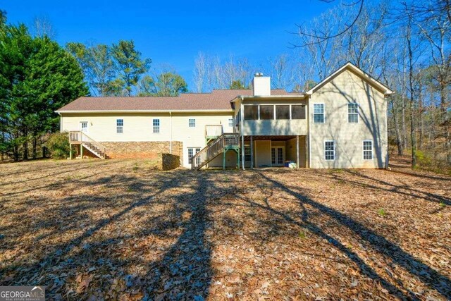 rear view of house featuring a sunroom and a deck