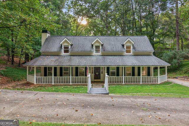 farmhouse-style home with a porch, a garage, an outbuilding, and a front yard