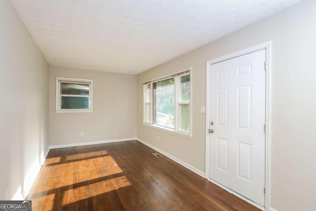 spare room with a textured ceiling and dark hardwood / wood-style floors