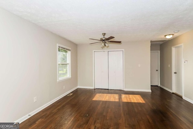 interior space with a textured ceiling, dark wood-type flooring, ceiling fan, and a closet