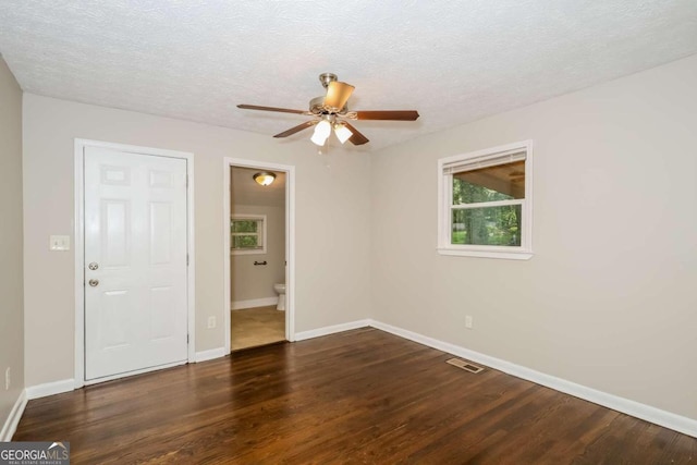 empty room featuring dark hardwood / wood-style flooring, ceiling fan, and a textured ceiling